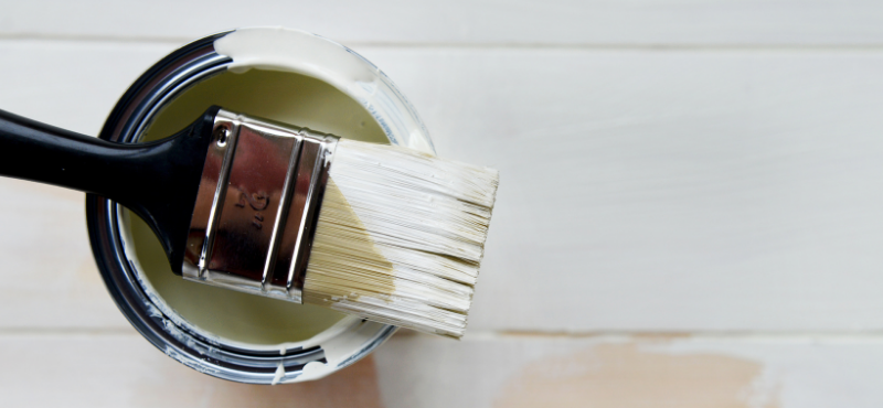 Purkillinen valkoista maalia, jonka päällä pensseli.