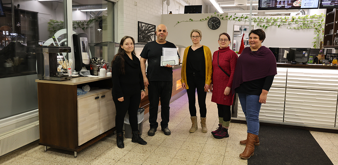 Limingan vammaisneuvosto ojentaa kunniakirjaa Pizzeria Adoran toimitusjohtajalle.