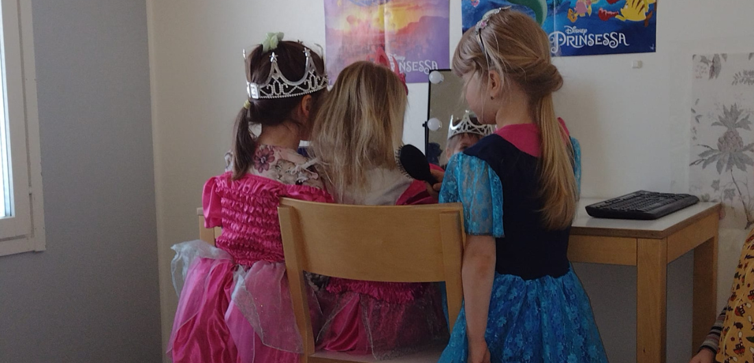 Prinsessoja leikkivät lapset pöydän ääressä.