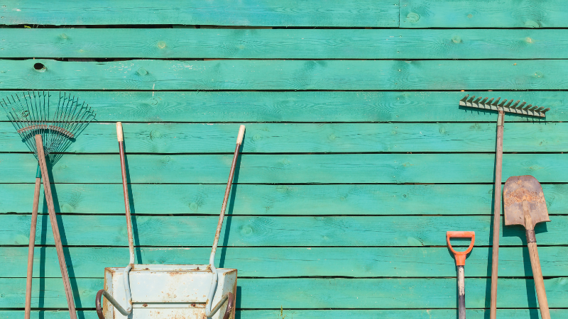 Kottikärryt ja työvälineet nojaavat lautaseinää vasten.