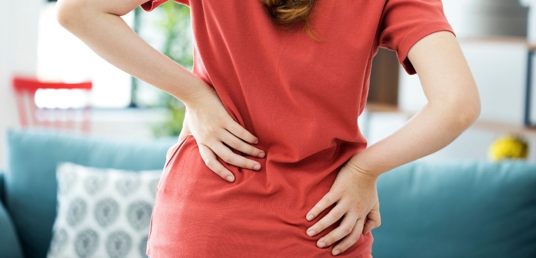 Ihminen pitelee kipeää selkäänsä.