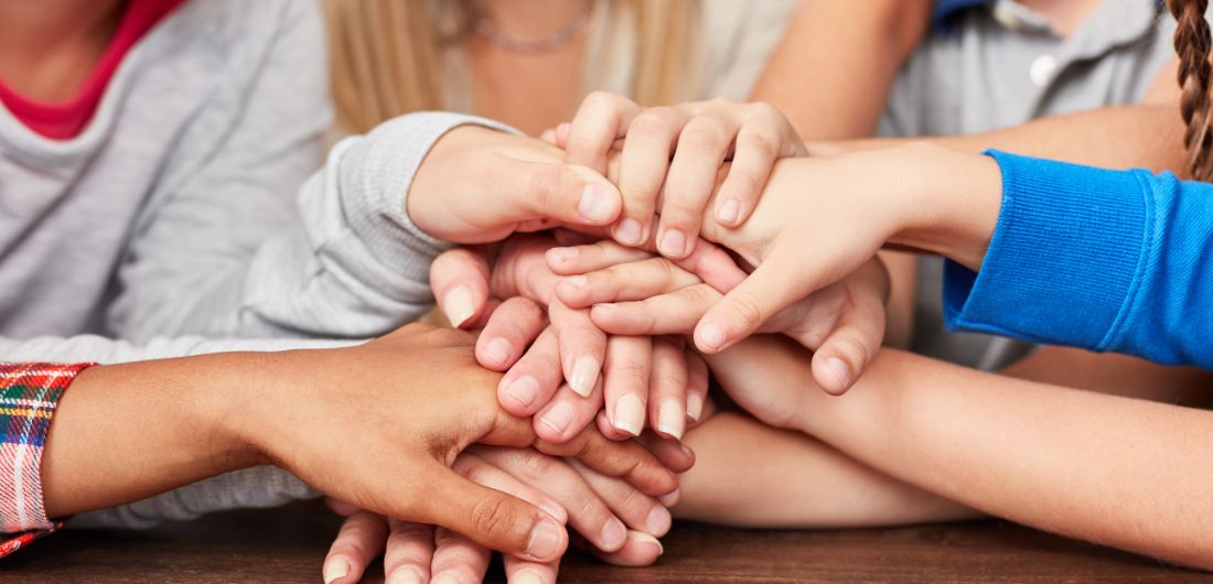 lasten ja aikuisten käsiä pöydällä päällekäin
