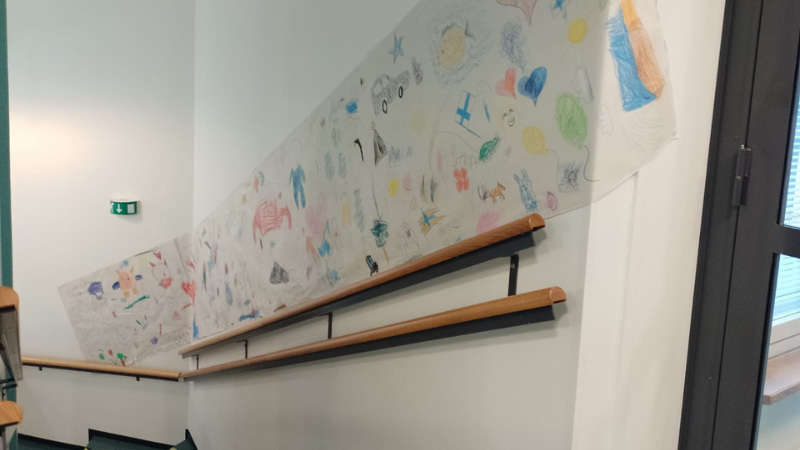 Portaikkoseinällä iso paperi, jossa piirrustuksia.