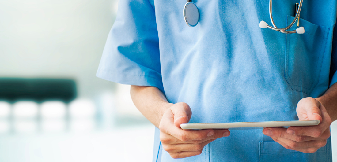 Terveydenhuollon ammattilainen seisoo stetoskooppi kaulan ympärillä tabletti käsissään.
