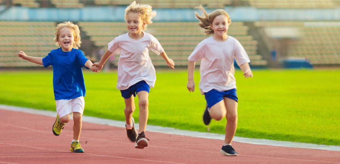 Lapset juoksevat urheilukentällä