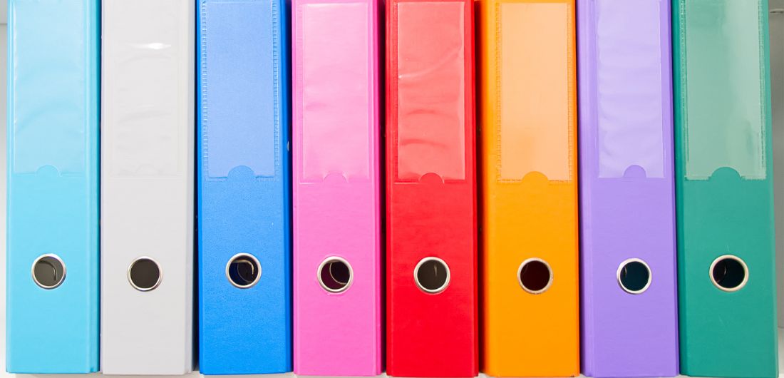 Värikkäät kansiot hyllyssä.