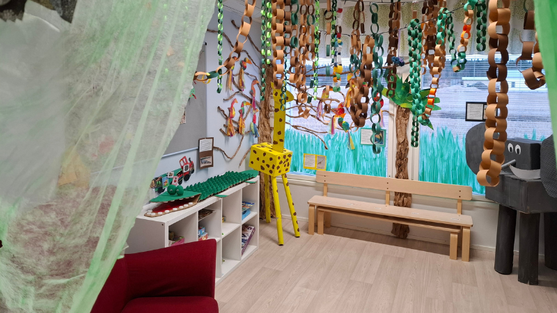 Aapin päiväkodin leikkinurkkauksessa on meneillään viidakkoleikki. Nurkassa lelukirahvi.